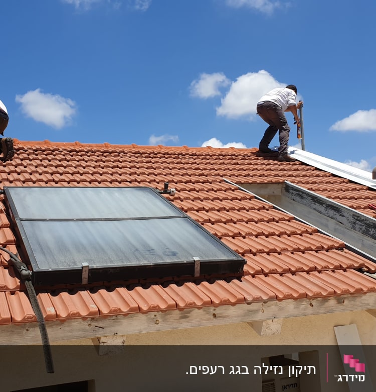 שני אנשים עובדים על גג רעפים עם קולטי שמש